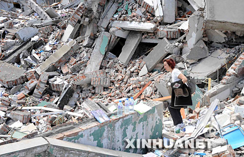 5月14日，一位妇女在四川北川县中学的废墟里呼唤寻找被埋在废墟里的亲属。 受汶川地震影响，四川北川中学的教学楼倒塌，众多师生被埋在倒塌的校舍中。 